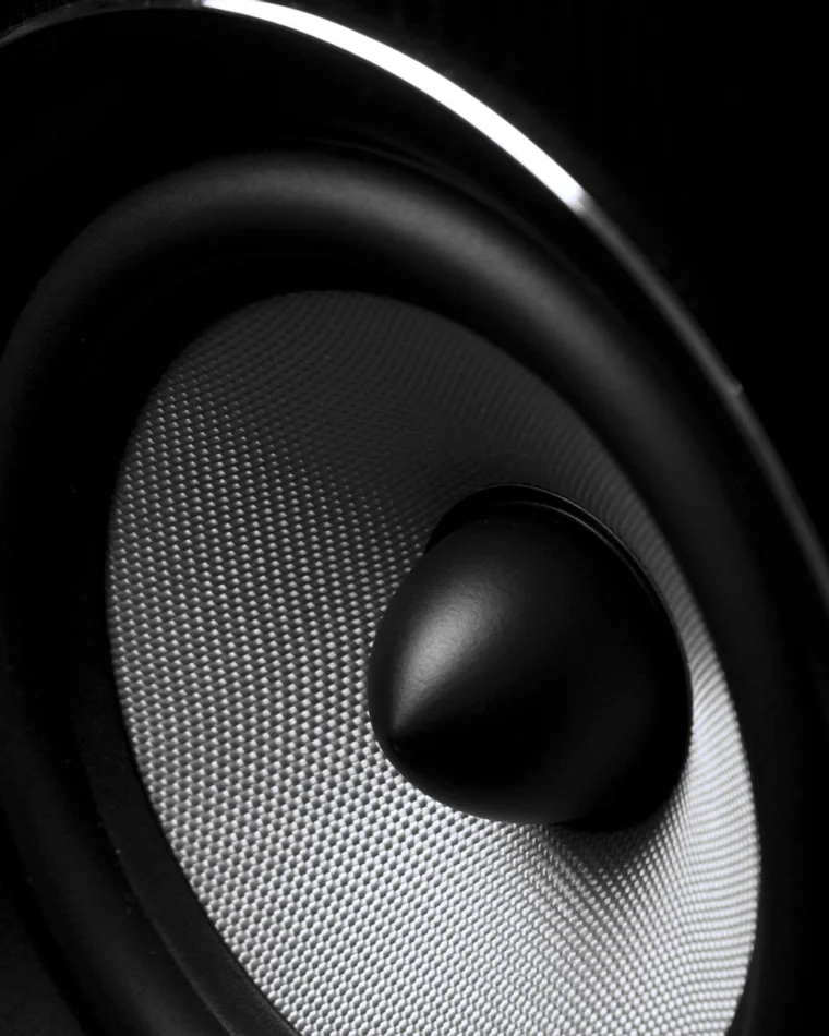 Close view of a speaker cone and dome under a cold studio light.