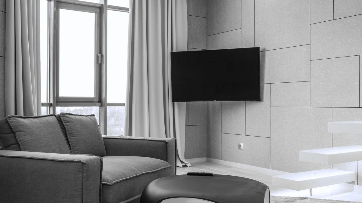 A living room with a low couch, a rug and a window along one wall.