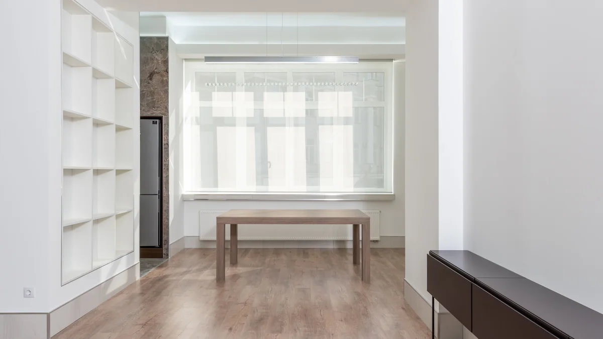 A spare room with a bare wooden table under a window.